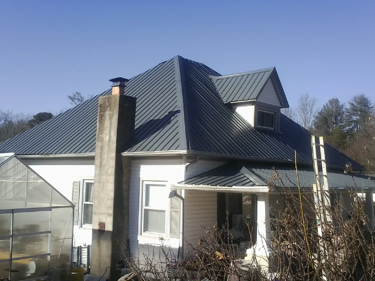 Dark blue standing seam metal roof on a white farmhouse with dormer — Slate & Tile Roof Repair by Roofing Brothers in Sumatra