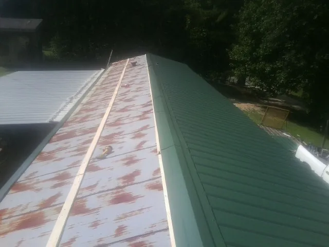 Old rusted panels beside newly installed green metal roofing — Wind Damage Roof Repair by Roofing Brothers in Sumatra