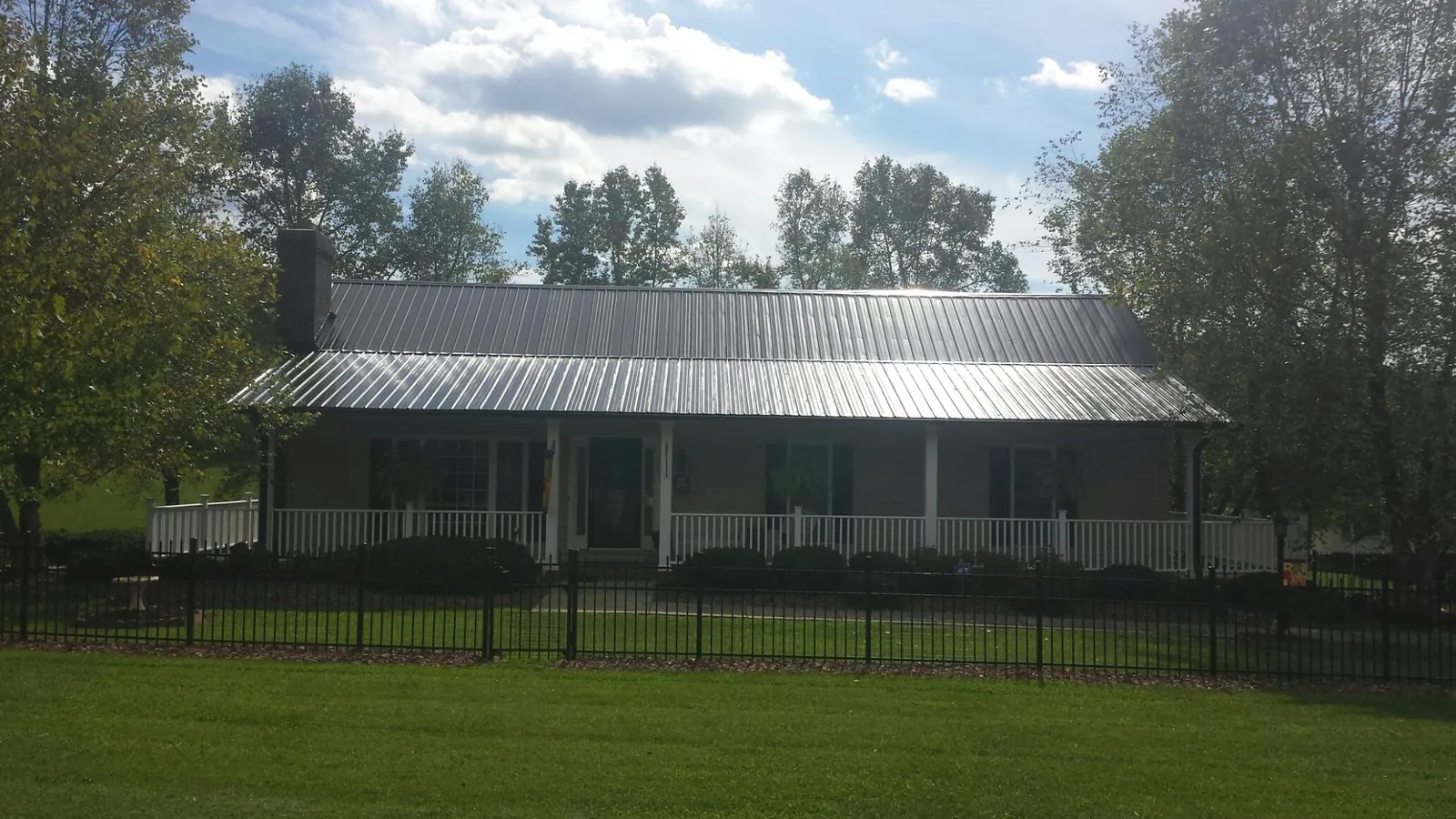 Gray metal roof on a brick ranch with a full width front porch — Gutter Guard Installation work by our crew in Sumatra