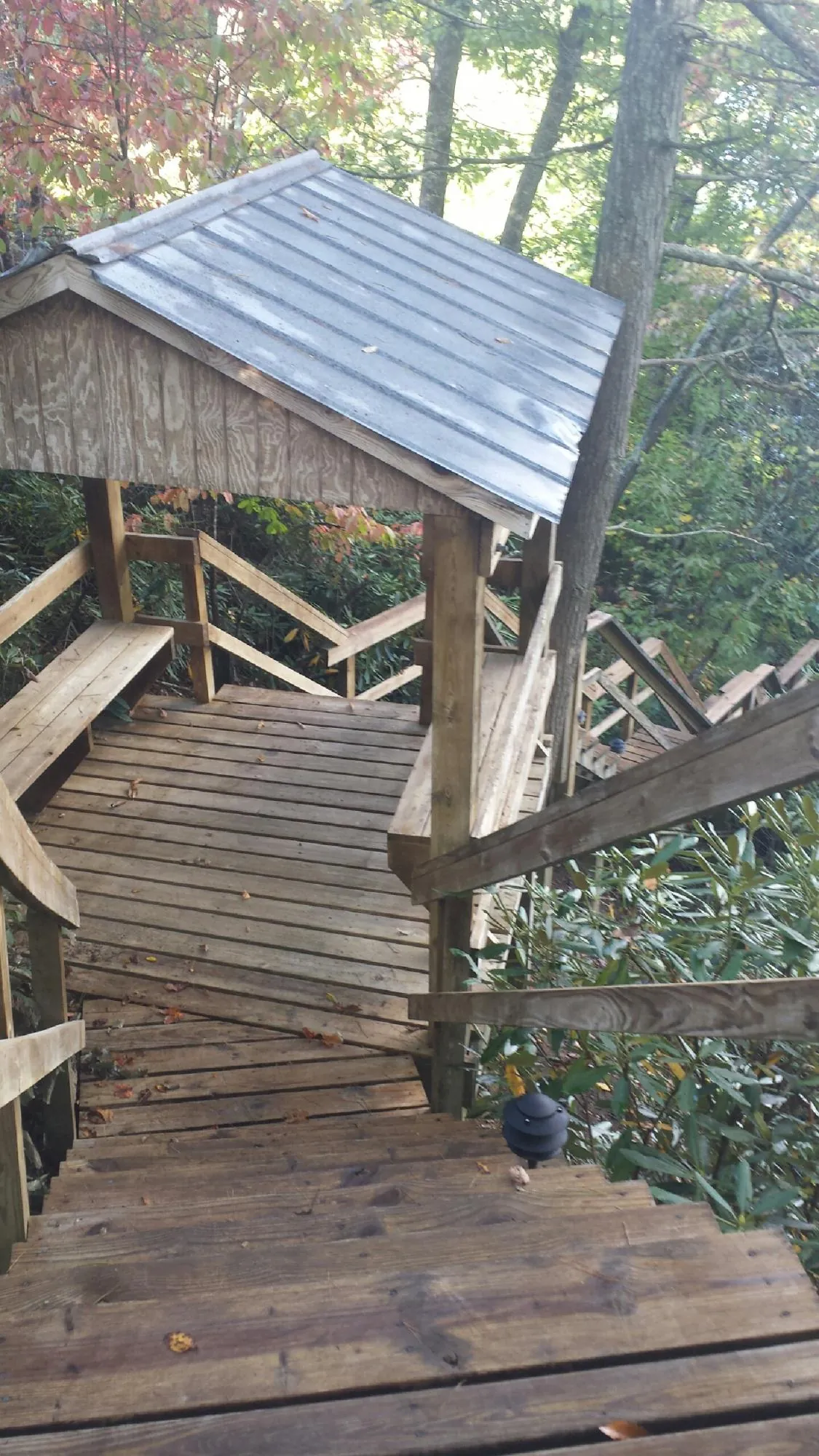 Metal roofed shelter over wooden steps on a wooded walkway — Skylight Repair & Installation work by our crew in Sumatra
